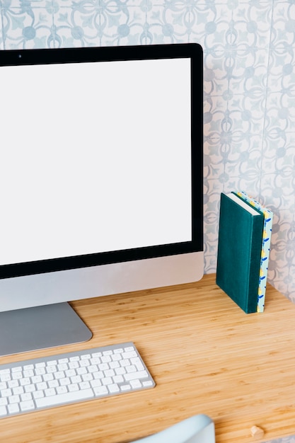 Computadora con pantalla en blanco en blanco en el escritorio de madera