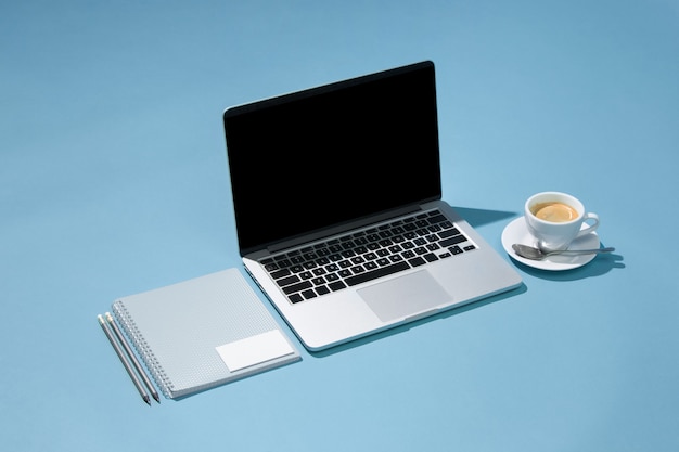La computadora portátil, bolígrafos, teléfono, nota con pantalla en blanco en la mesa