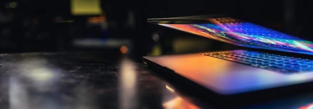 Foto gratuita una computadora portátil a mitad cerrada en la oscuridad con un brillo colorido