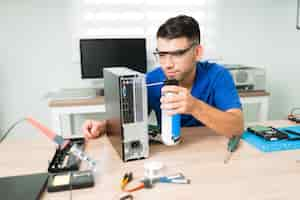 Foto gratuita computadora sucia. atractivo joven con gafas de protección mientras limpia el interior con aire comprimido el hardware de una computadora