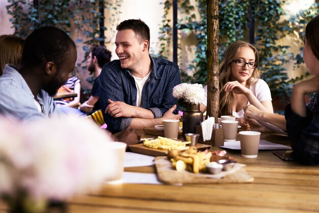 Comunicándose con colegas multiculturales en el pequeño y acogedor restaurante local con deliciosa comida.