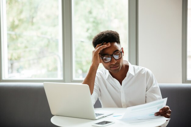 Concentrado serio joven africano sentado coworking