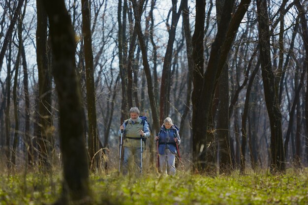 Concentrado y serio. Pareja de familia de hombre y mujer en traje de turista caminando en el césped cerca de árboles en un día soleado. Concepto de turismo, estilo de vida saludable, relajación y convivencia.