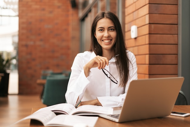 Concentrado en el trabajo. Mujer hermosa joven que usa su computadora portátil mientras está sentado. Hermosa inteligente linda encantadora atractiva elegante dueña femenina tiene reunión en línea en el interior