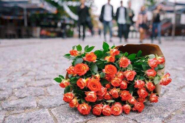 Concéntrese en un ramo de rosas en papel artesanal en una calle gris pavage