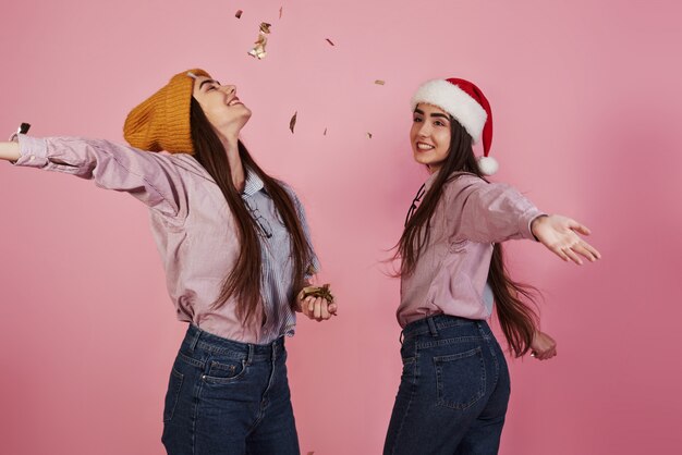 Concepción de año nuevo. Dos gemelos jugando lanzando confeti dorado en el aire