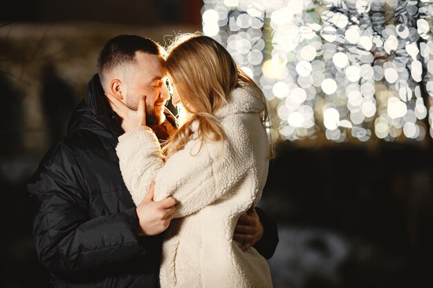 Concepción de las vacaciones de invierno. Retrato nocturno al aire libre de una pareja joven. Posando en la calle de la ciudad europea.