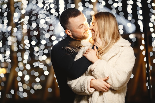 Concepción de las vacaciones de invierno. retrato nocturno al aire libre de una pareja joven. posando en la calle de la ciudad europea.