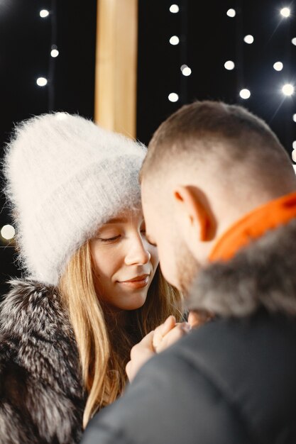 Concepción de las vacaciones de invierno. Retrato nocturno al aire libre de una pareja joven. Posando en la calle de la ciudad europea.