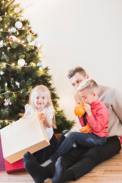 Concept de navidad con padre e hijos al lado de árbol de navidad