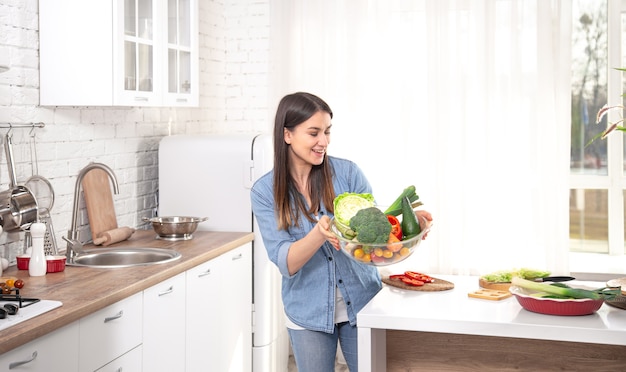 Concepto de alimentación saludable. Mujer hermosa joven en la cocina con frutas y verduras.Comida vegana