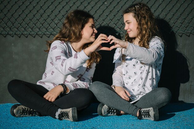 Concepto de amistad con chicas jóvenes sentadas en azotea