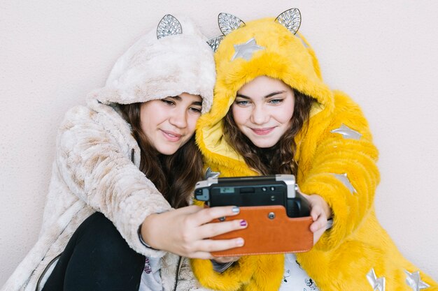 Concepto de amistad con dos chicas haciendo selfie con cámara instantánea