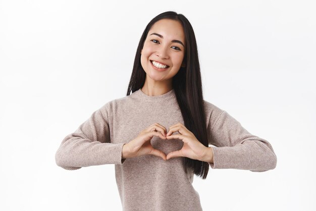 Concepto de amor y romance familiar Atractiva niña asiática sonriente prepara un regalo conmovedor para la madre en las vacaciones Día de la madre o Navidad Apreciar una relación conmovedora Expresar emociones agradecidas