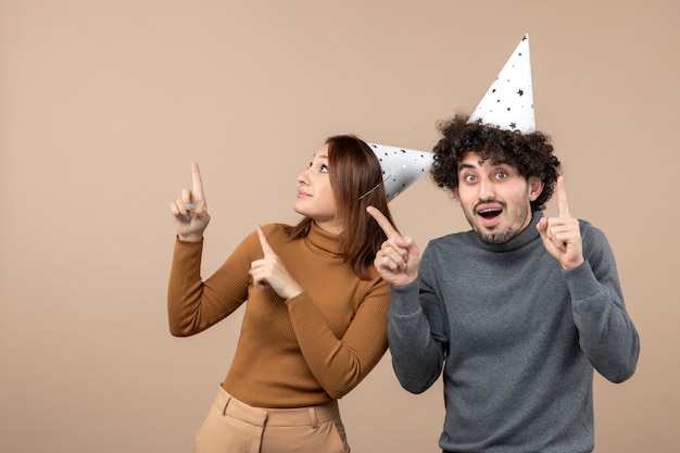 Concepto de año nuevo con encantadora pareja joven feliz emocionada usar sombrero de año nuevo en imagen gris