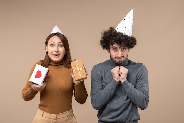 Concepto de año nuevo con feliz pareja joven usar sombrero de año nuevo chica emocional con corazón