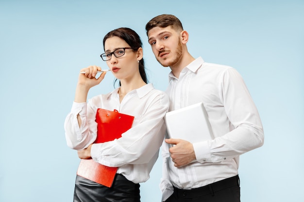 Concepto de asociación empresarial. Joven emocional y mujer sobre fondo azul en el estudio. Las emociones humanas y el concepto de asociación