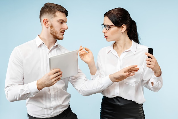 Foto gratuita concepto de asociación empresarial. joven emocional y mujer sobre fondo azul en el estudio. las emociones humanas y el concepto de asociación