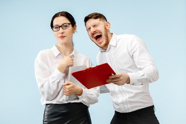 Concepto de asociación empresarial. Joven sonriente feliz y mujer de pie contra la pared azul