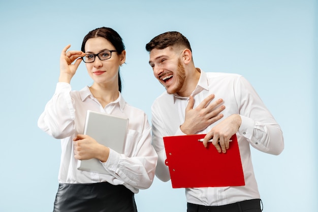 Concepto de asociación empresarial. Joven sonriente feliz y mujer de pie contra la pared azul