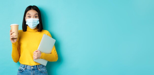 Foto gratuita concepto de atención médica y cuarentena de covid estudiante asiática con máscara médica de pie con computadora portátil y