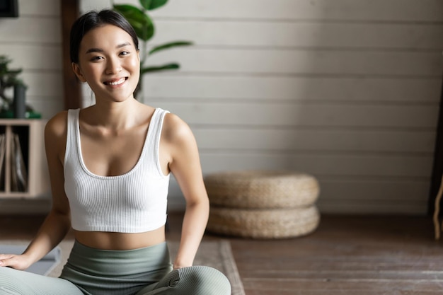 Concepto de atención plena y meditación joven mujer asiática haciendo ejercicio en casa meditación de yoga en la sala de estar ...