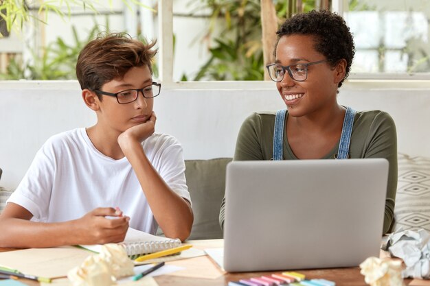 Concepto de autoeducación y aprendizaje electrónico. Voluntaria negra satisfecha intenta explicar su estrategia a una joven estudiante