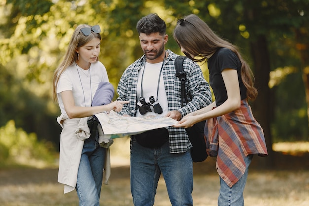 Concepto de aventura, caminata y personas. Grupo de amigos sonrientes en un bosque. Hombre con binoculares.