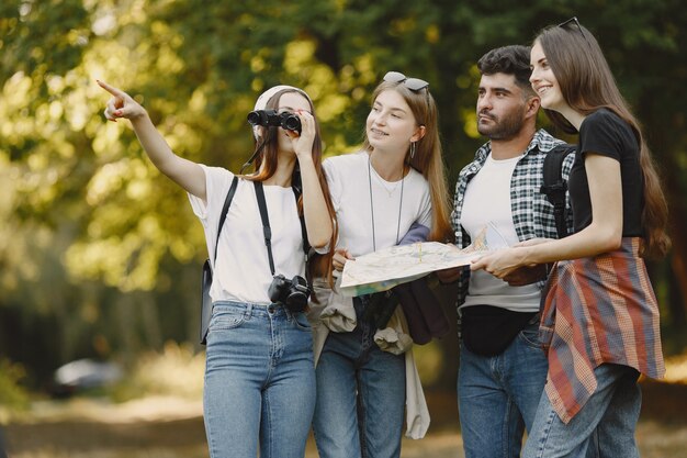 Concepto de aventura, viajes, turismo, caminata y personas. Grupo de amigos sonrientes en un bosque. Hombre con binocularus.