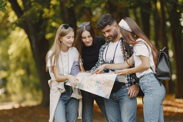 Concepto de aventura, viajes, turismo, caminata y personas. Grupo de amigos sonrientes en un bosque. Hombre con binocularus.