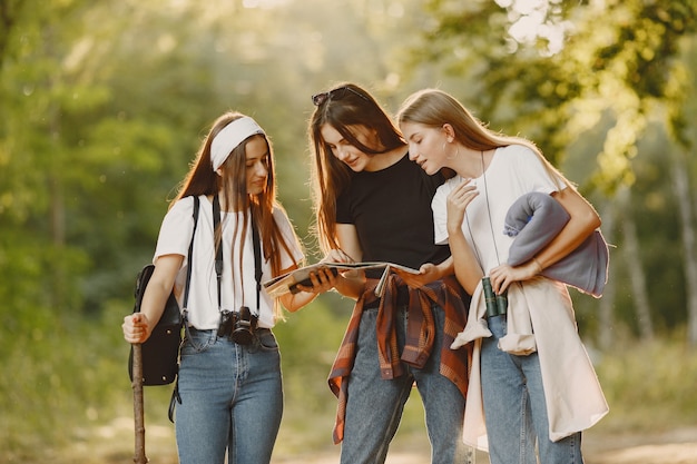 Concepto de aventura, viajes, turismo, caminata y personas. Tres chicas en un bosque.