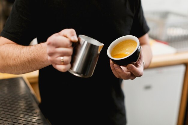 Concepto de bar con barista poniendo leche en café