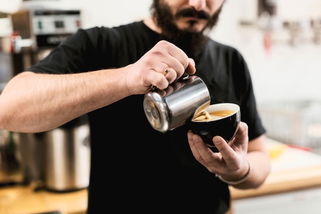 Concepto de bar con barista poniendo leche en café