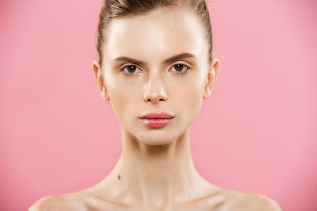 Concepto de belleza - Close up Retrato de niña caucásica atractiva con la piel de belleza natural aislado en fondo de color rosa con copia espacio.