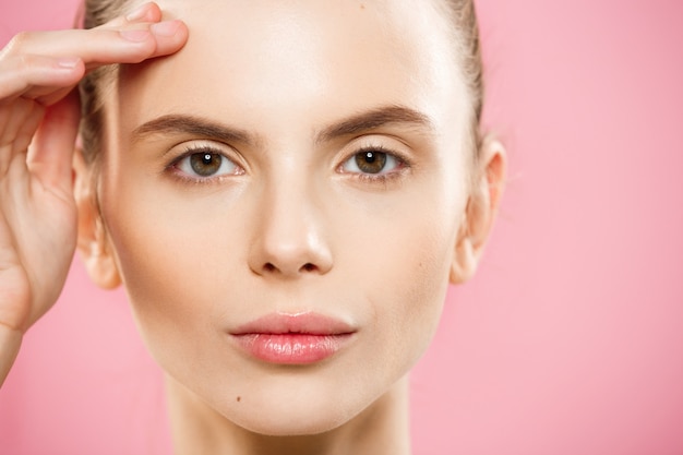 Concepto de belleza - Close up Retrato de niña caucásica atractiva con la piel de belleza natural aislado en fondo de color rosa con copia espacio.