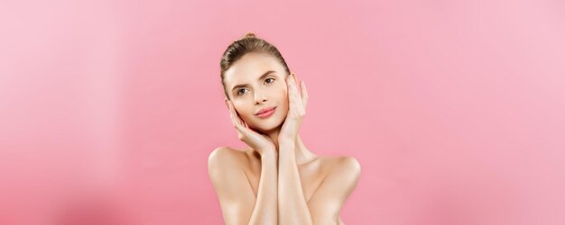 Concepto de belleza Hermosa mujer caucásica con maquillaje natural de piel limpia aislado sobre fondo rosa brillante con espacio de copia