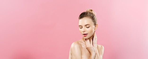 Concepto de belleza Hermosa mujer caucásica con maquillaje natural de piel limpia aislado sobre fondo rosa brillante con espacio de copia