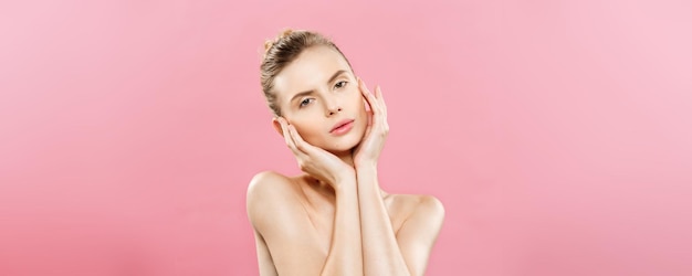 Concepto de belleza Hermosa mujer caucásica con maquillaje natural de piel limpia aislado sobre fondo rosa brillante con espacio de copia