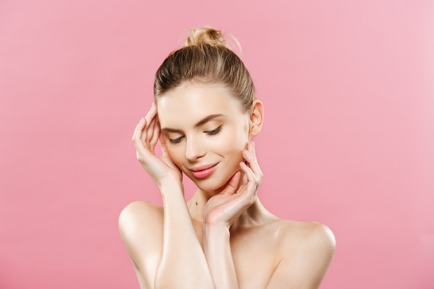 Concepto de belleza - Hermosa mujer con piel fresca limpia de cerca en el estudio de color rosa. Cara del cuidado de la piel. Cosmetología.