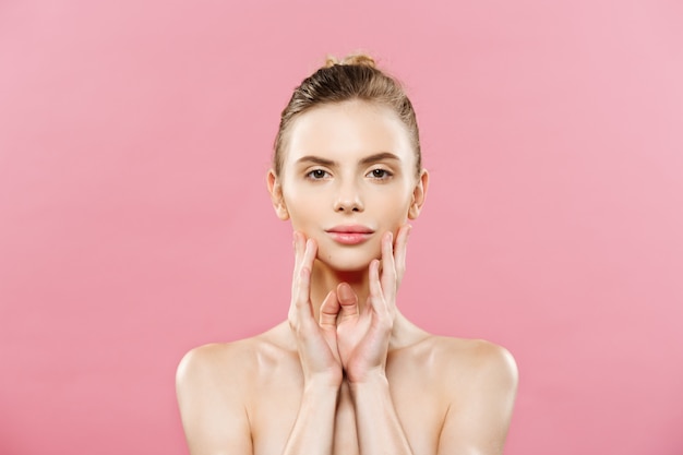 Concepto de belleza - Hermosa mujer con piel fresca limpia de cerca en el estudio de color rosa. Cara del cuidado de la piel. Cosmetología.