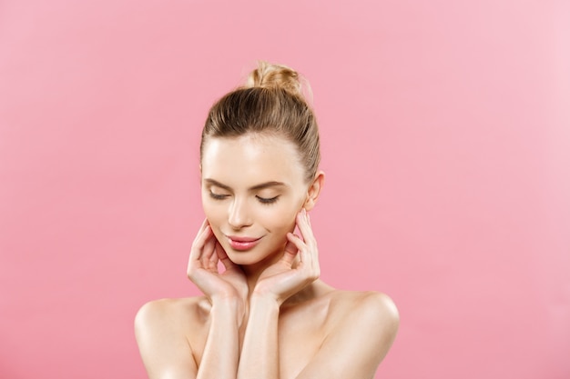 Concepto de belleza - Hermosa mujer con piel fresca limpia de cerca en el estudio de color rosa. Cara del cuidado de la piel. Cosmetología.