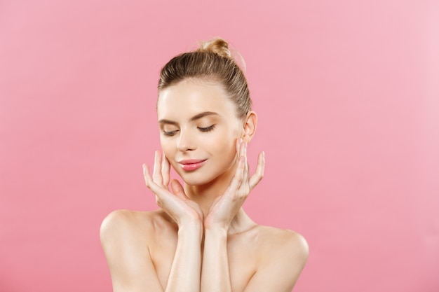 Concepto de belleza - Hermosa mujer con piel fresca limpia de cerca en el estudio de color rosa. Cara del cuidado de la piel. Cosmetología.