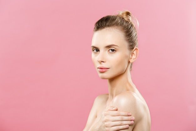 Concepto de belleza - Hermosa mujer de raza caucásica con piel limpia, maquillaje natural aislado en fondo de color rosa brillante con copia espacio.