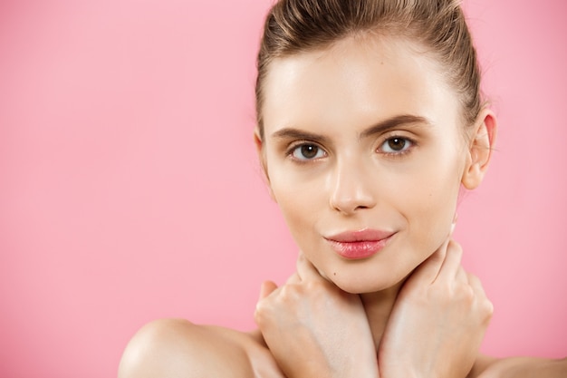 Concepto de belleza - Hermosa mujer de raza caucásica con piel limpia, maquillaje natural aislado en fondo de color rosa brillante con copia espacio.