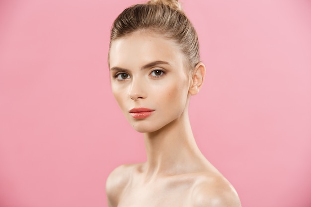 Concepto de belleza - Hermosa mujer de raza caucásica con piel limpia, maquillaje natural aislado en fondo de color rosa brillante con copia espacio.