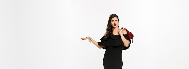 Foto gratuita concepto de belleza y moda de longitud completa de mujer arrogante y atrevida en vestido negro con bolso en s
