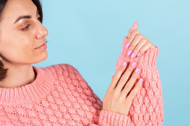 Concepto de belleza, mujer bonita con manicura de color de uñas rosa brillante en la pared