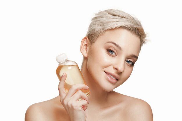 Concepto de belleza la mujer bonita con una piel perfecta con botella de aceite