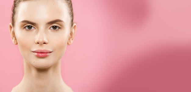 Concepto de belleza Primer plano Retrato de atractiva chica caucásica con piel natural de belleza aislada sobre fondo rosa con espacio de copia