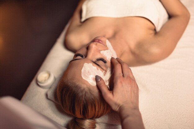 Concepto de bienestar con mujer con crema en la cara